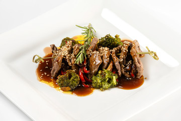 Closeup plate of delicious beef meat with brocolli, pepper and sauce isolated at white background.