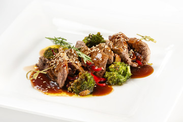 Closeup plate of delicious beef meat with brocolli, pepper and sauce isolated at white background.