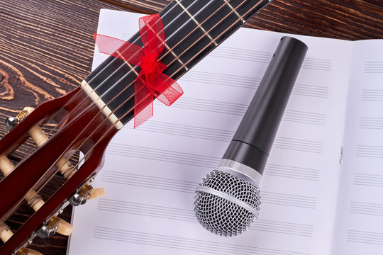 Guitar, notes sheet and microphone. Vocal microphone on music notes. Musical equipment for concert.