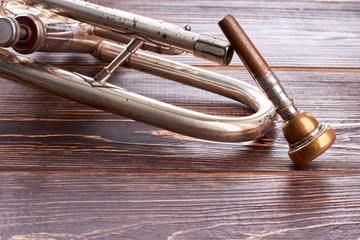 Vintage trumpet on wooden background. Rusty cornet on brown wooden surface. Classical music tool.