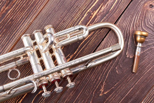 Silver trumpet on brown wooden background. Musical trumpet with clipping path. Classical musical instrument.