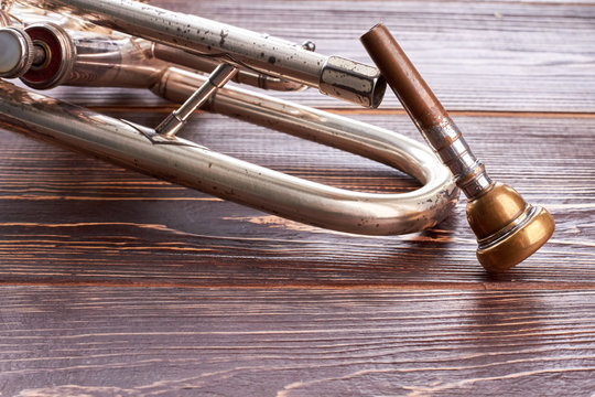 Vintage trumpet on wooden background. Rusty cornet on brown wooden surface. Classical music tool.