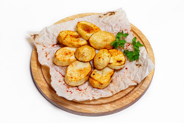 Fried potato wedges on a wooden tray board with paper isolated at white background.