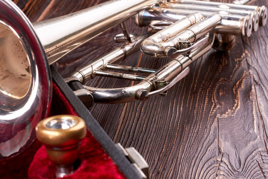 Old trumpet on textured wooden background. Rusty trumpet on brown wooden surface. Classical music instrument.