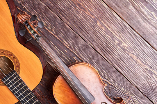 Classical violin and guitar on wooden background. Jazz guitar, violin and copy space. Traditional musical instruments.