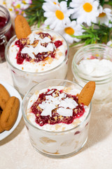dessert in a glass with cookies, cream and berries jam on table