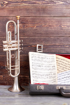 Trumpet and musical notes on wooden background. Classical jazzy instrument. Symbol of music.