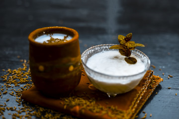 Traditional summer drink i.e. is most popular in Asia and India i.e. Chas or chaas or buttermilk or chhaachh in a clay glass with curd and coriander powder and salt on wooden surface,Close up.