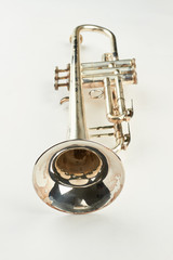 Old trumpet on white background, vertical image. Vintage trumpet instrument. Jazz music equipment.