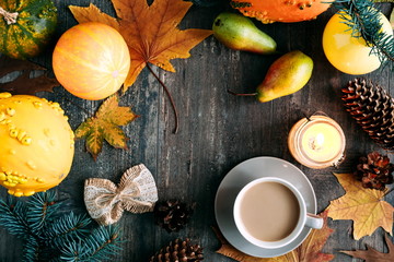 Autumn composition. Thanksgiving day concept. Cup of coffee, pear, candle, pumpkins, red and yellow leaves on dark wooden vintage background. Autumn, fall, background. Flat lay, top view, copy space 