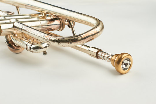 Rusty trumpet with mouthpiece close up. Part of classical trumpet on light background. Design of retro jazzy instrument.