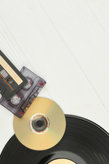 Musical storage devices and text space. Top view on vinyl record, DVD disc, audio cassette tapes on...