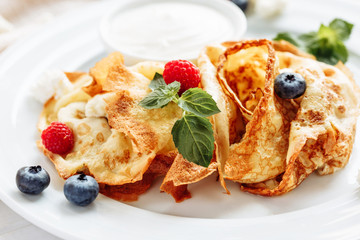 closeup of pancakes with cottage cheeseand strawberry, blueberry on plate on white plate background, decorated with mint leaves