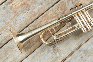 Fototapeta premium Aged trumpet on wooden planks. Old trumpet on vintage wooden background. Instrument of classical music.