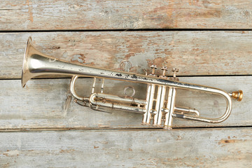 Rusty trumpet on rustic wooden background. Still life old trumpet. Fanfare musical instrument.