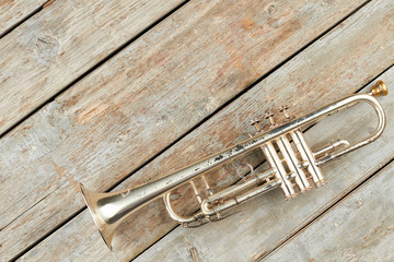 Fototapeta na wymiar Old trumpet and copy space. Rusty trumpet on old wooden boards. Classical music pipe instrument.