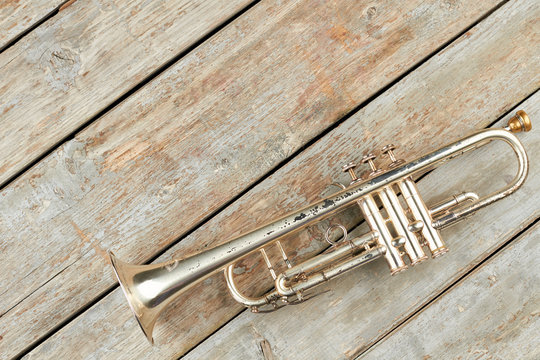Old trumpet and copy space. Rusty trumpet on old wooden boards. Classical music pipe instrument.