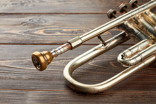 Aged trumpet on wooden background. Old trumpet with brassy mouthpiece. Classical music instrument.