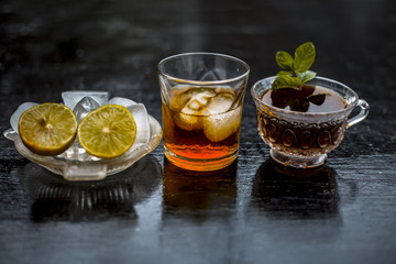 Close up of hangover remedy i.e. lemon juice and black tea in a transparent cup on wooden surface with Scotch or Scotch whiskey or Grain whiskey.