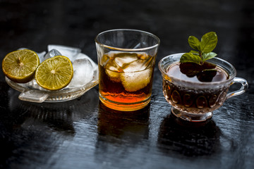 Close up of hangover remedy i.e. lemon juice and black tea in a transparent cup on wooden surface with Scotch or Scotch whiskey or Grain whiskey.