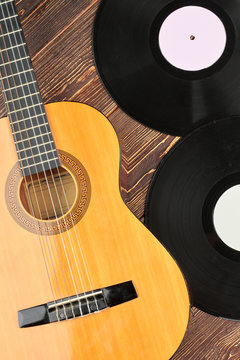 Wooden background with musical objects. Acoustic guitar and vinyl records, vertical image.