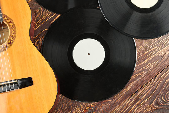 Vinyl records and guitar on wooden surface. Gramophone vinyl plates and acoustic guitar. Music retro style.