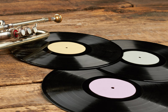 Vinyl plates on rustic wooden background. Trumpet and three vinyl records. Music retro style.