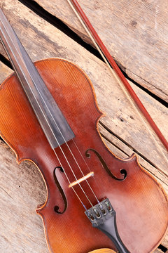Antique violin on old wooden boards. Vintage cello and fiddle stick. Instrument of symphony orchestra.