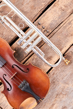 Old musical instruments of symphony orchestra. Trumpet and violin on grunge wood. Professional musical instruments in retro style.
