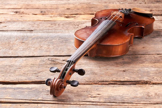 Violin on old wooden floor. Classical musical instrument on rustic wooden boards. Musical equipment of orchestra.