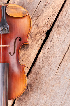 Old violin and copy space. Vintage style violin on wooden floor, vertical image. Classic orchestral instrument.