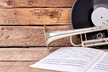 Classic music equipment on wooden background. Trumpet, vinyl record and music papers on old wooden...