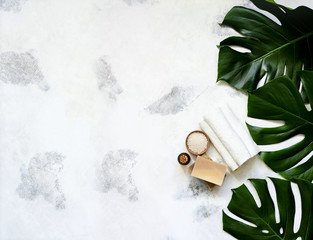Spa and massage treatments on white, marble background monstera leaves.