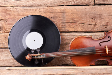 Vinyl record and vintage violin. Retro violin on old rustic wood. Black vinyl plate. Musical background in vintage style.