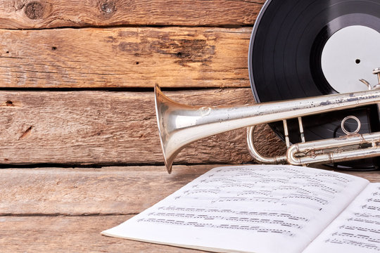Classic music equipment on wooden background. Trumpet, vinyl record and music papers on old wooden boards.