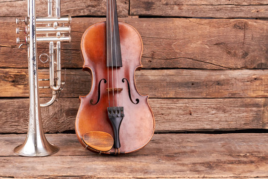 Trumpet, violin and copy space. Classical music instruments on rustic wooden floor.