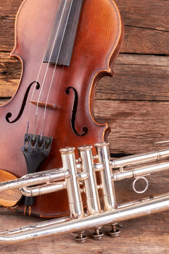 Old violin and trumpet on rustic wood. Classic music equipment in retro style. Instruments of symphony orchestra.