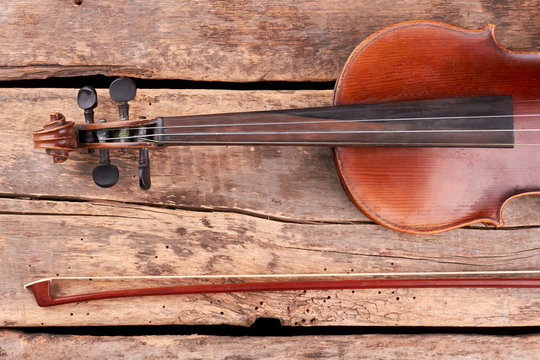 Violin and fiddle stick, cropped image. Part of vintage violin. Scroll and peg box. Classical musical instrument on rustic boards.