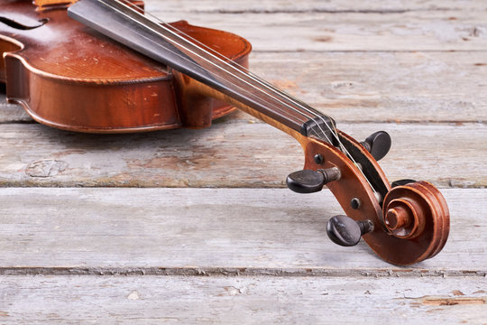 Violin on old wood, cropped image. Violin scroll and peg box. Classical orchestral instrument.