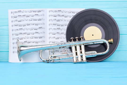 Vinyl records, trumpet and musical notes. Vinyl disc, rusty trumpet and musical papers on blue wood. Vintage musical equipment.