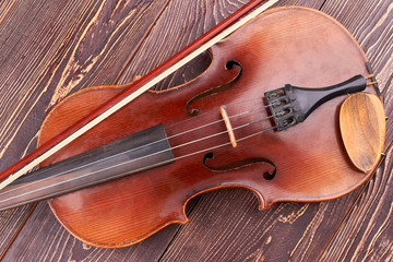 Brown violin on wooden table. Vintage violin and fiddle stick. Symbol of classical music.