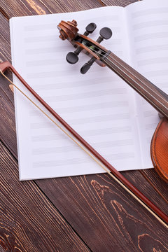 Violin, bow and musical notes pages. Classical music objects on wooden background, vertical image. Violin practice tips.