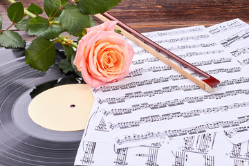 Musical sheets, vinyl record and rose. Musical instruments and rose on wooden background. Music...