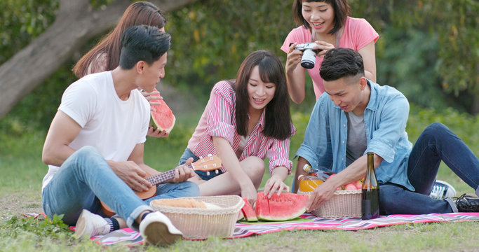 Friends go picnic together in the park and enjoy the food and drink