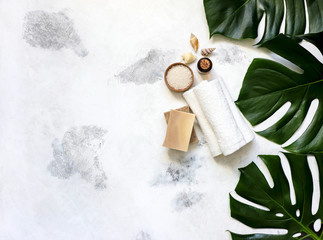 Spa and massage treatments on white, marble background monstera leaves.