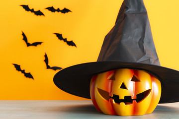 Pumpkin with a witch hat with orange background. Halloween concept.