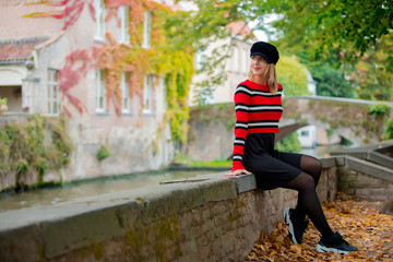 Young girl in hat at bridge in Bruges, Belgium. Autumn season.