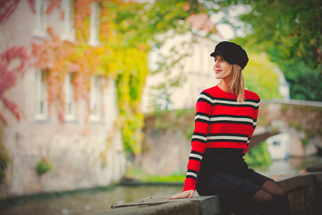Young girl in hat at bridge in Bruges, Belgium. Autumn season.