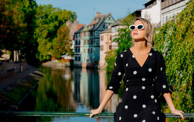 Young style girl in black dress stay near channel in Strasbourg, France, Autumn season time