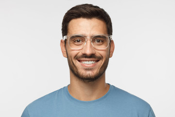 Close up shot of smiling attractive man in blue t-shirt and trendy trasparent eyeglasses isolated...